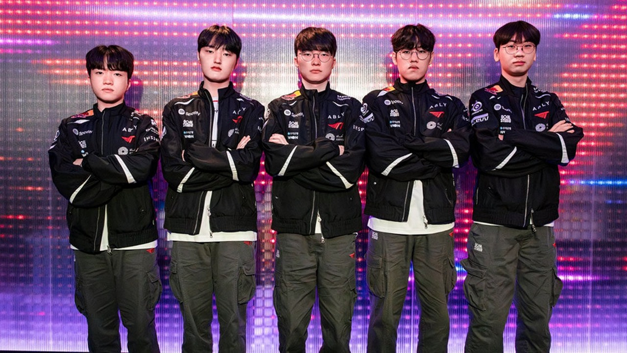 Five T1 players stand together in black team jackets