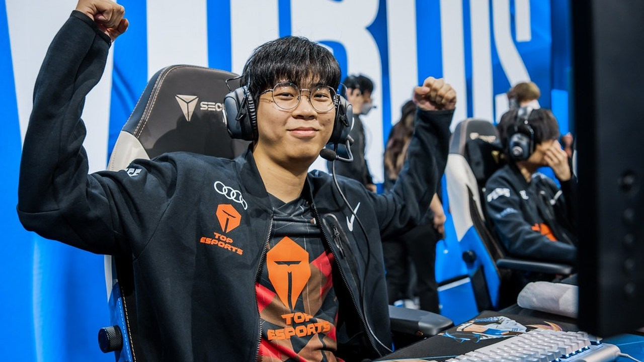A Top Esports player raises his fist at a tournament computer